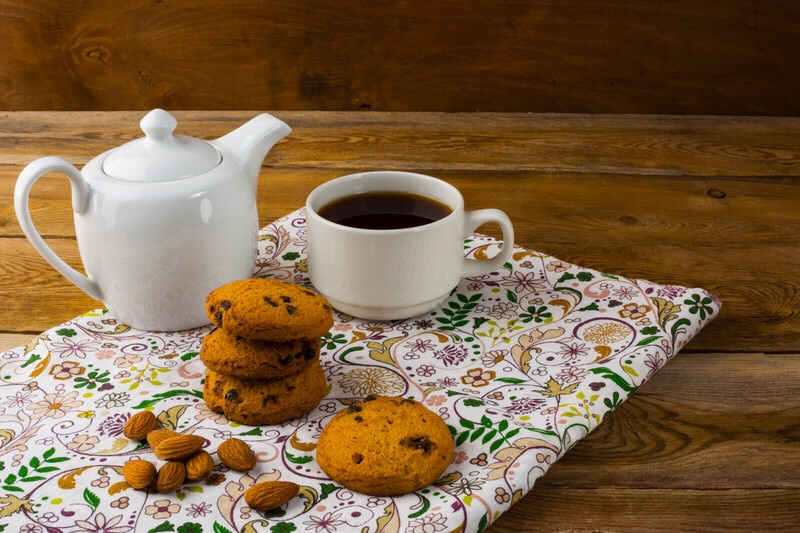 A cup of tea with a tea pot and pastries.