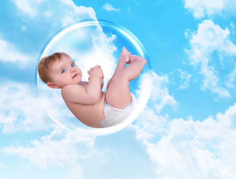 A baby floating inside a protective bubble in the clouds.