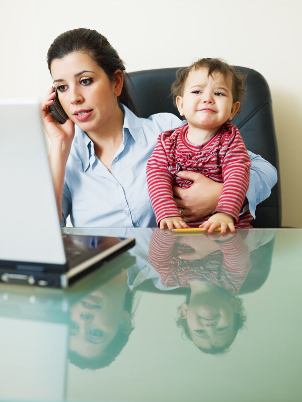 A busy mom working while playing with her daughter.