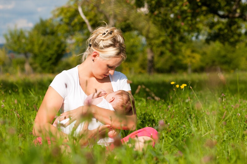 Mother nursing baby in a meadow.