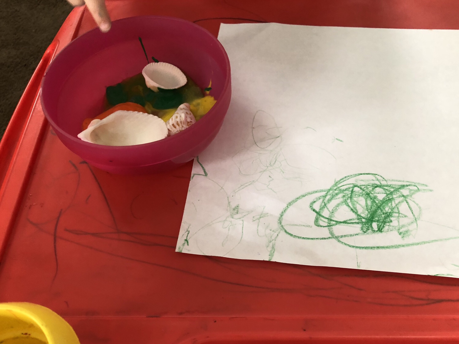 Three shells sitting in a bowl of paint next to a piece of paper.