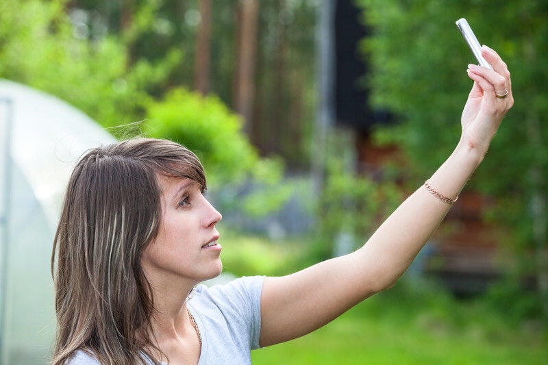 Woman holding up cell phone looking for coverage.