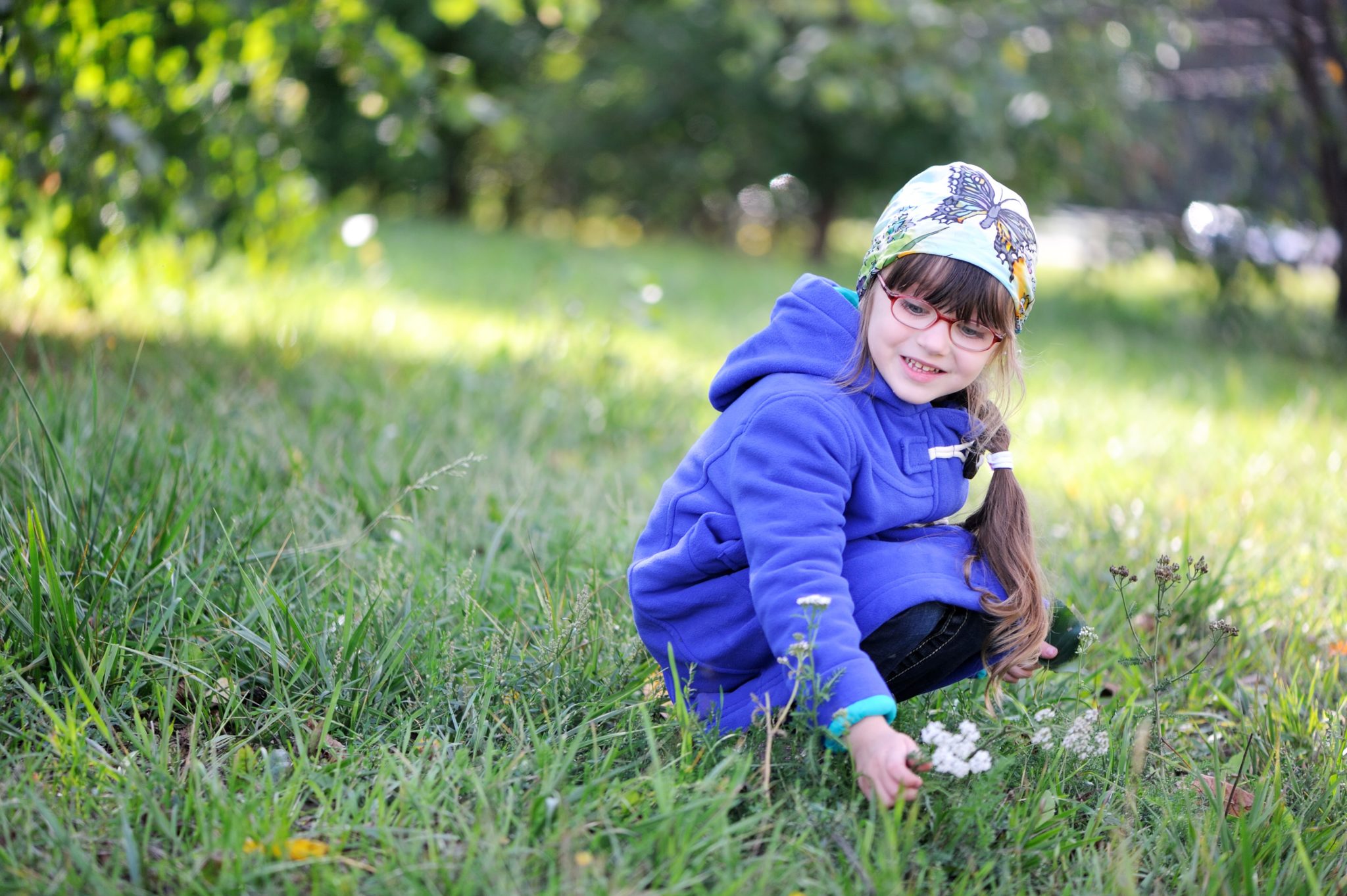 Little girl picking up flower.