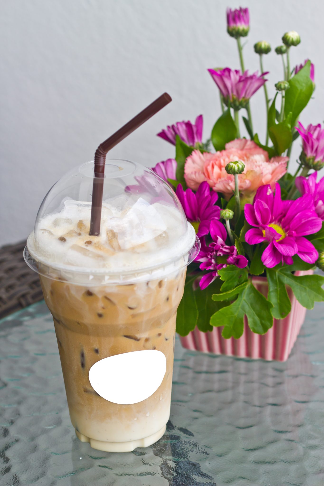 Iced coffee with a vase of flowers.