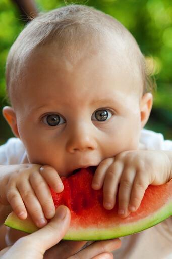 Baby boy eating water melon.