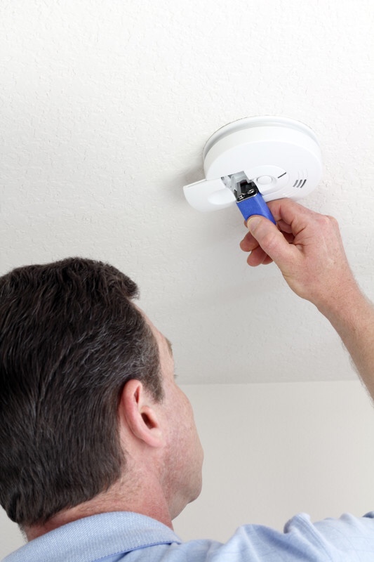 A man replacing the batteries in a smoke detector for home safety