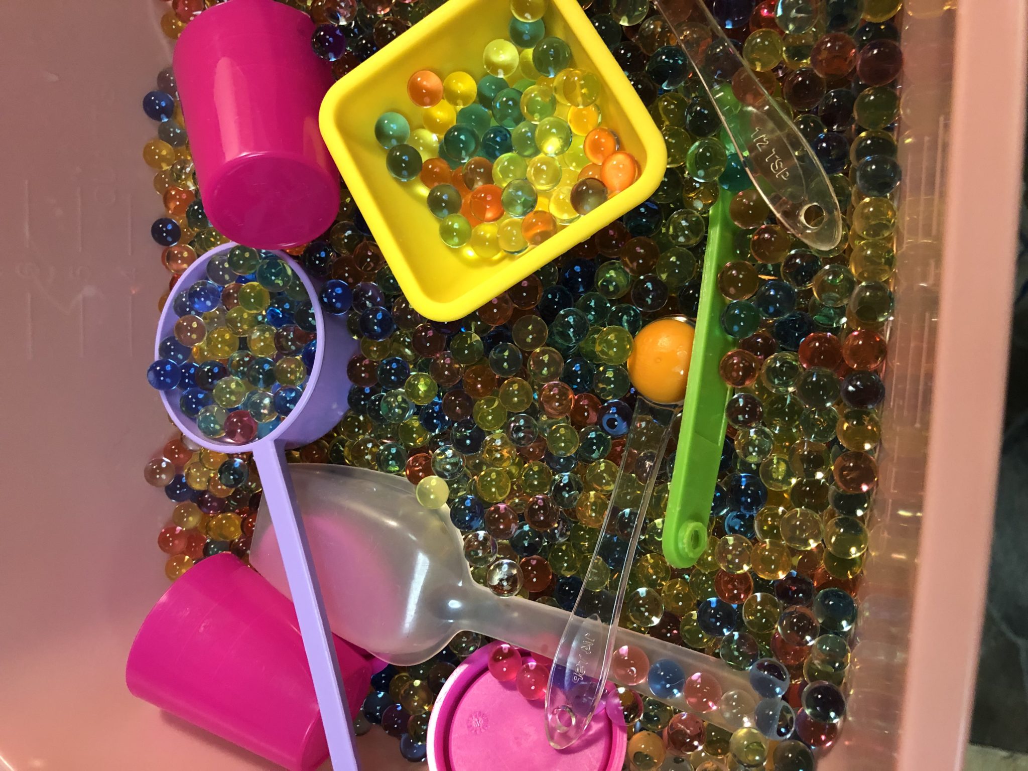 Sensory tub with water beads, scoops and cups.