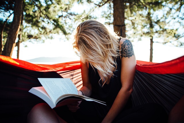 Woman relaxing and reading in hammock