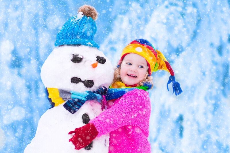 Toddler girl playing with snowman