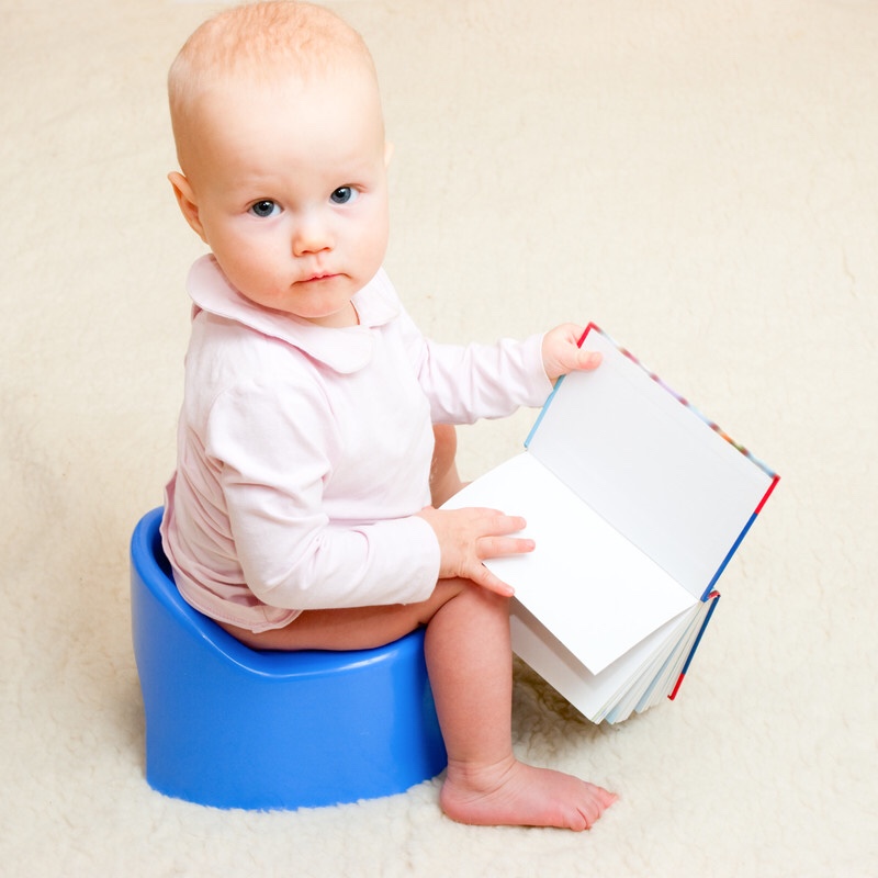 Toddler on the potty with an open book.