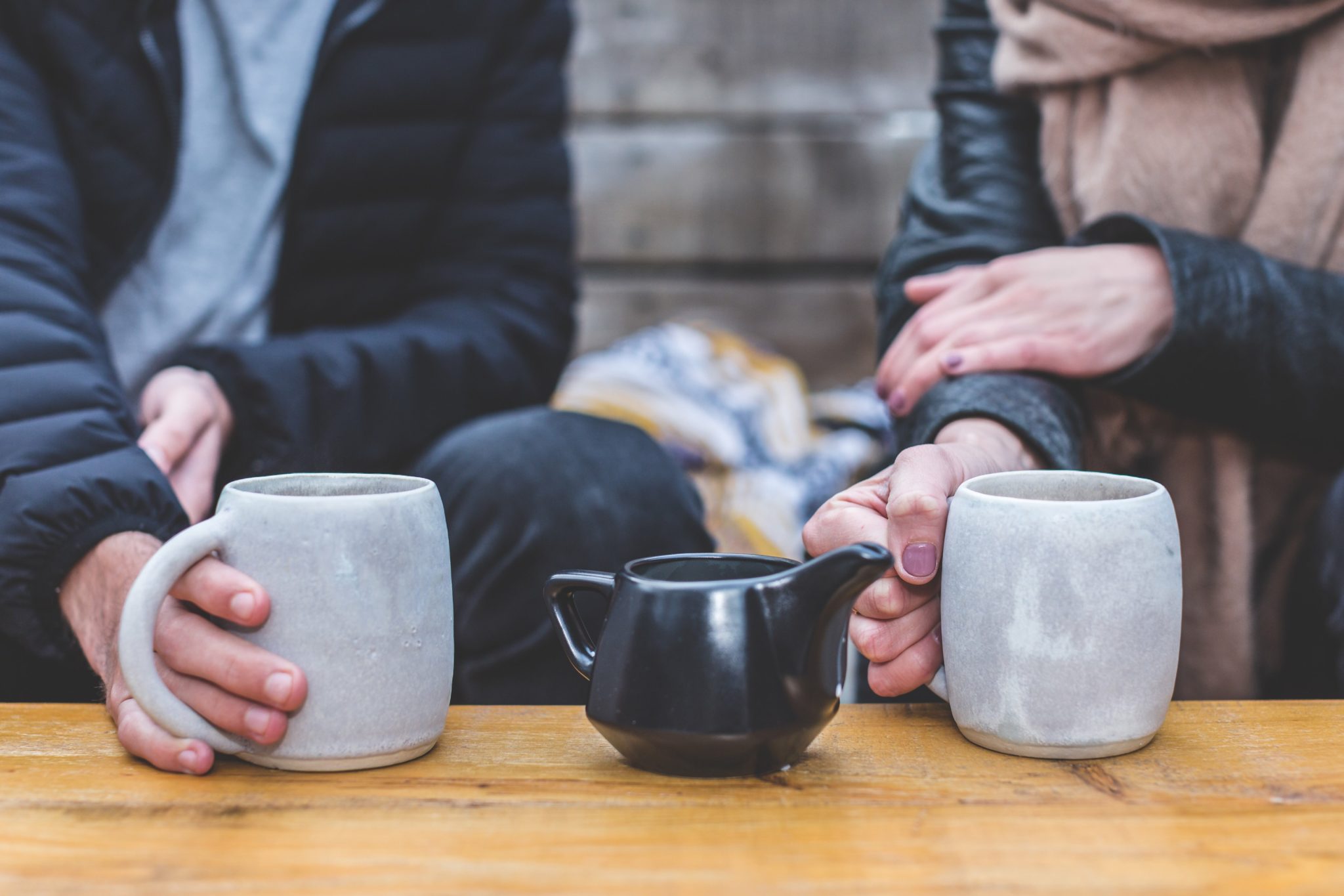 Couple with cups of coffee and creamer between them