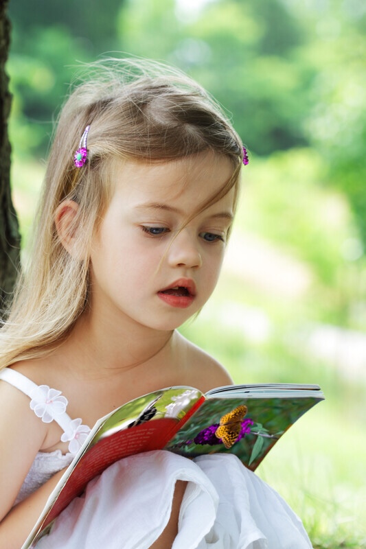 Little girl under tree reading book