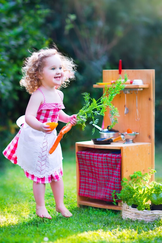 Little girl playing with toy kitchen