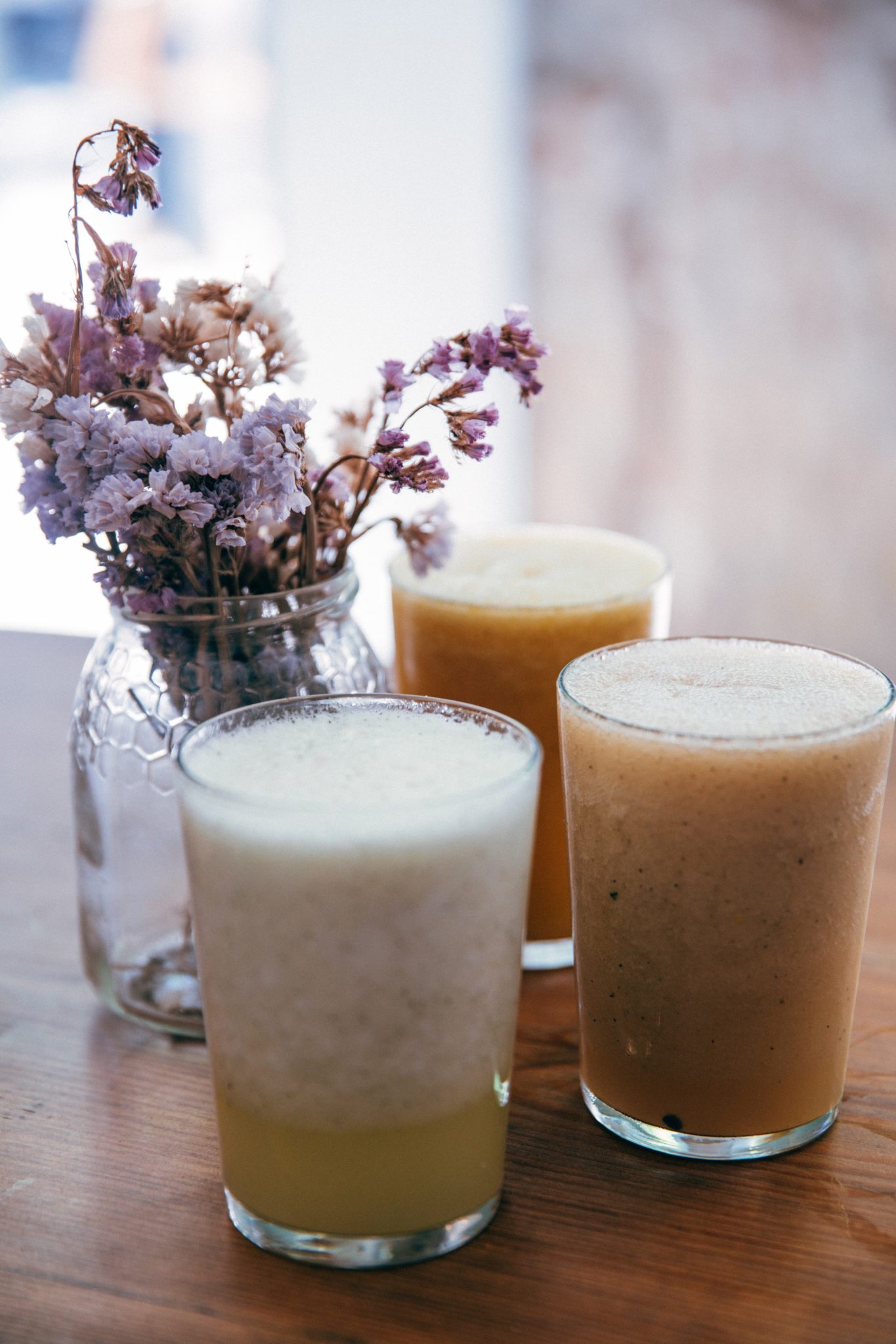 Fruit smoothie and juice next to flowers