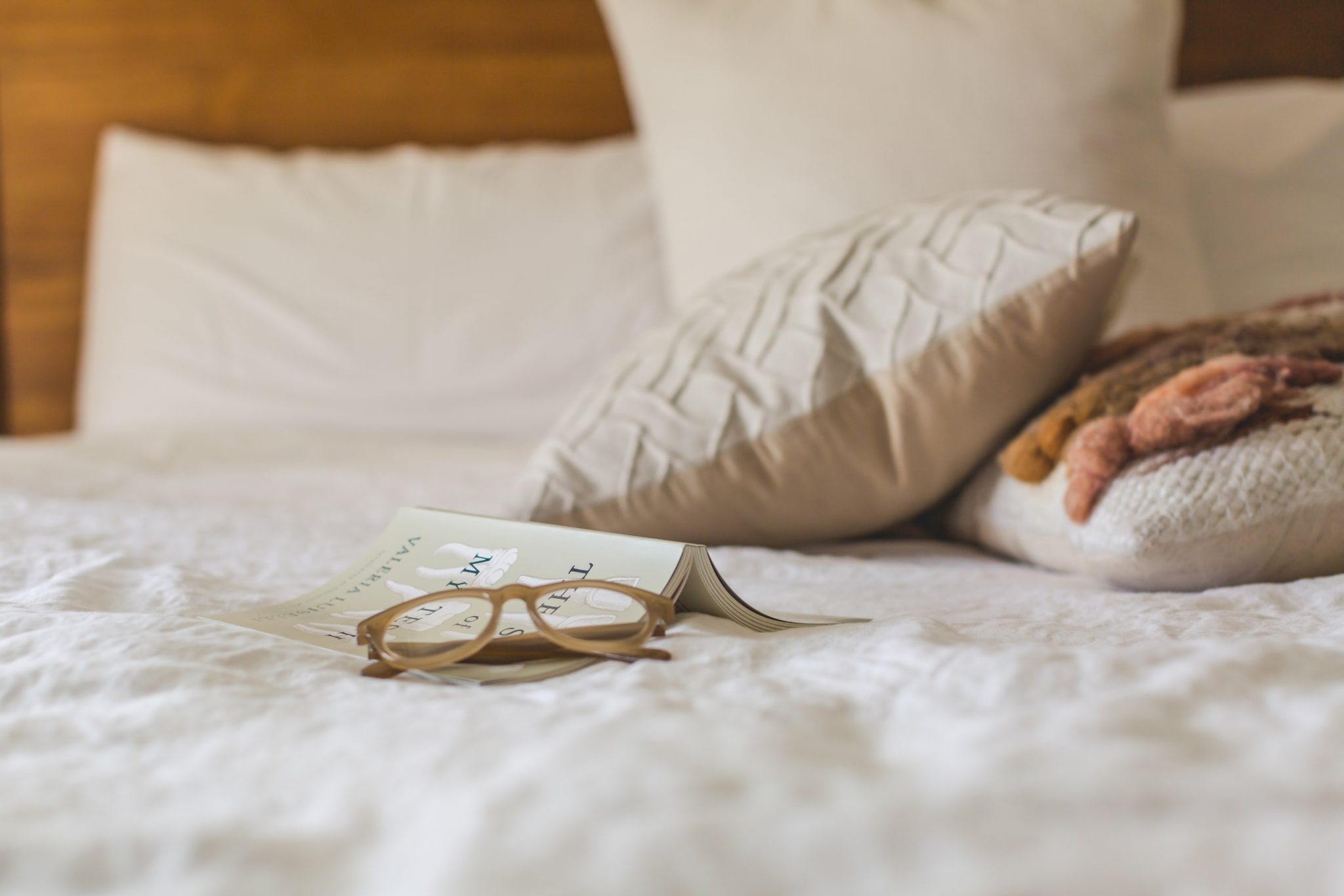 A Pillow with glasses and a book ready to be read.