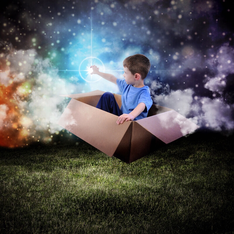 Boy floating in cardboard box reaching for a glowing star.