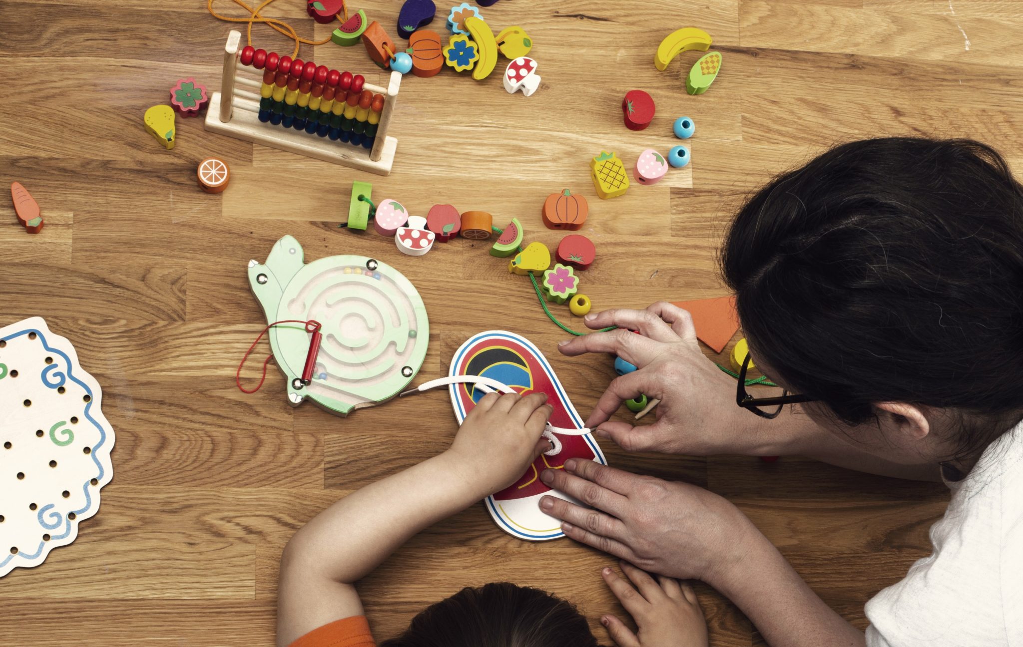 Teacher and child practicing tying shoes with toy