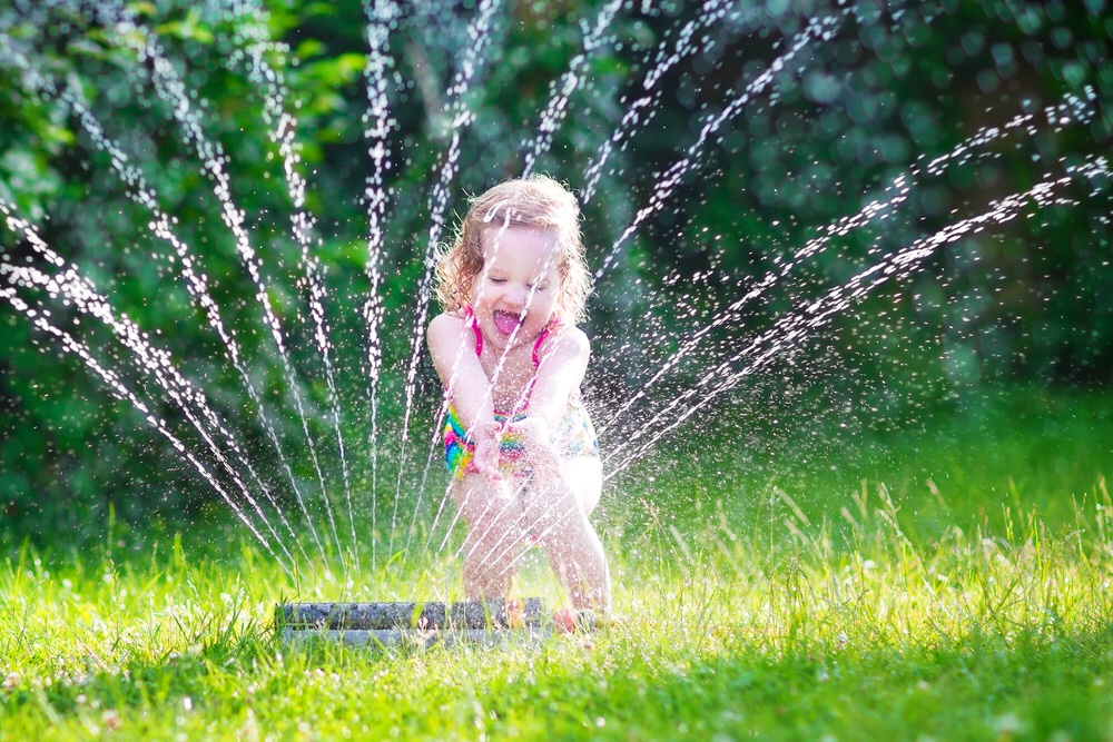 Little girl playing with sprinkler