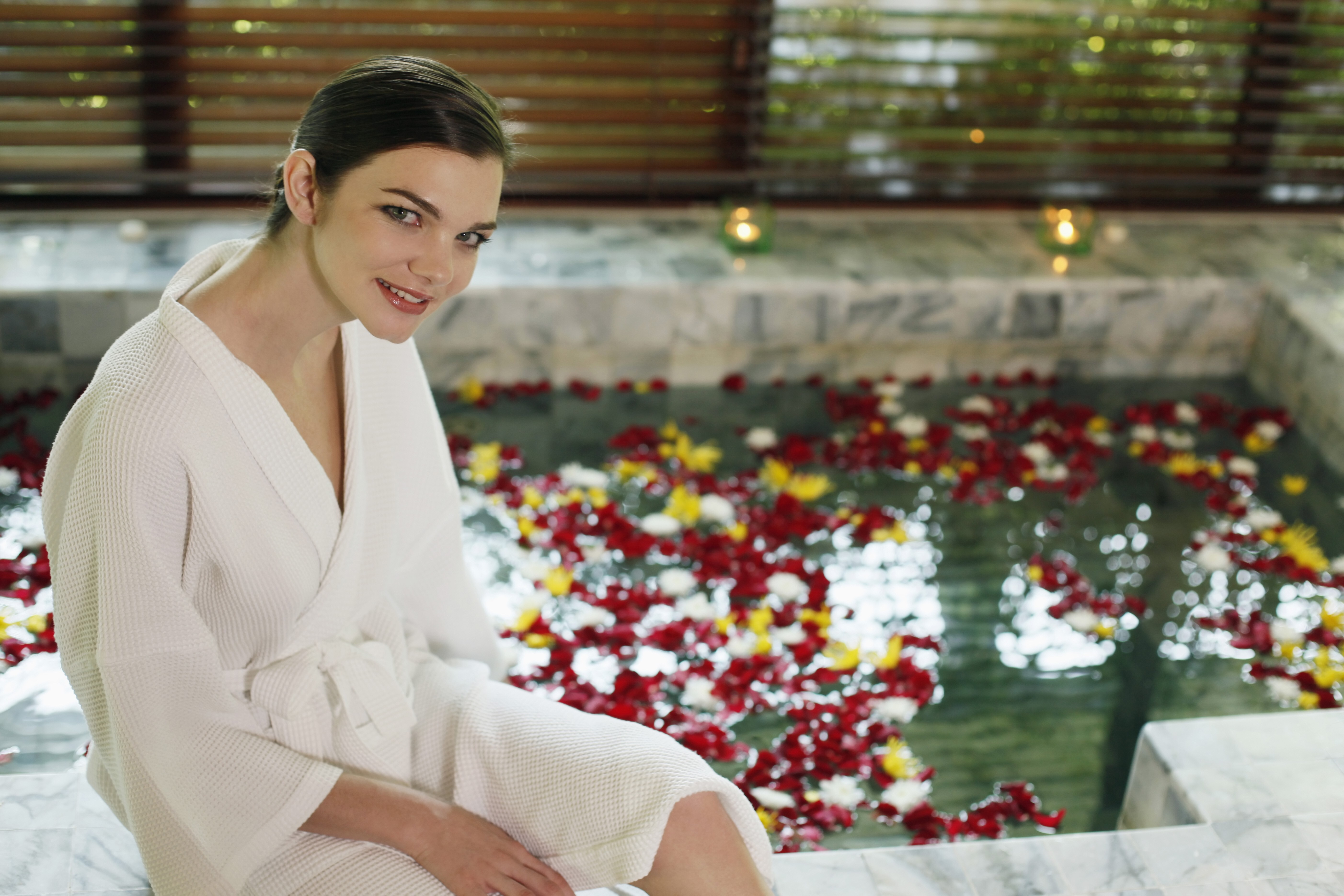 Woman sitting on a bath tub with rose petals.