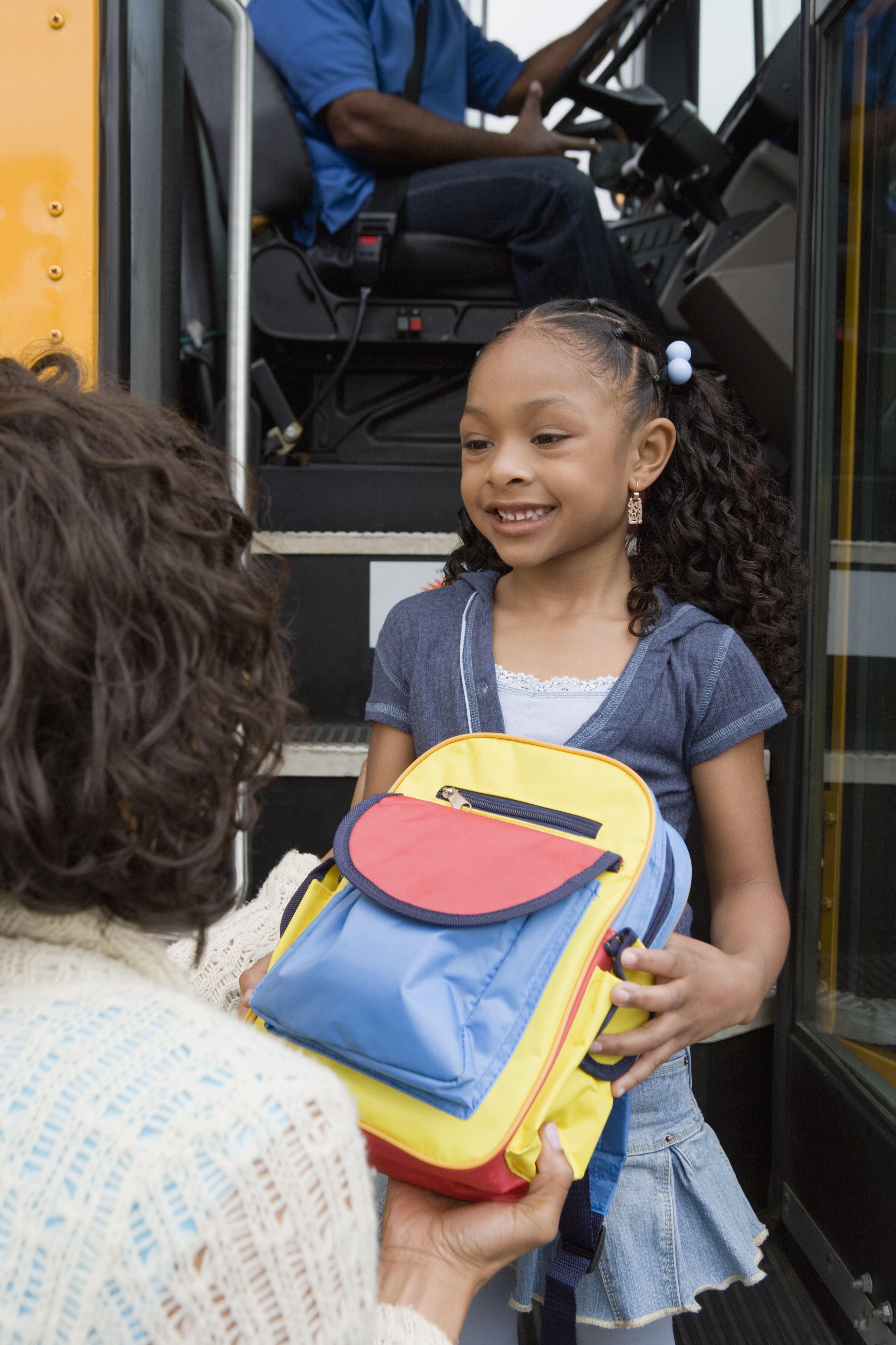 Mother giving backpack to daughter.