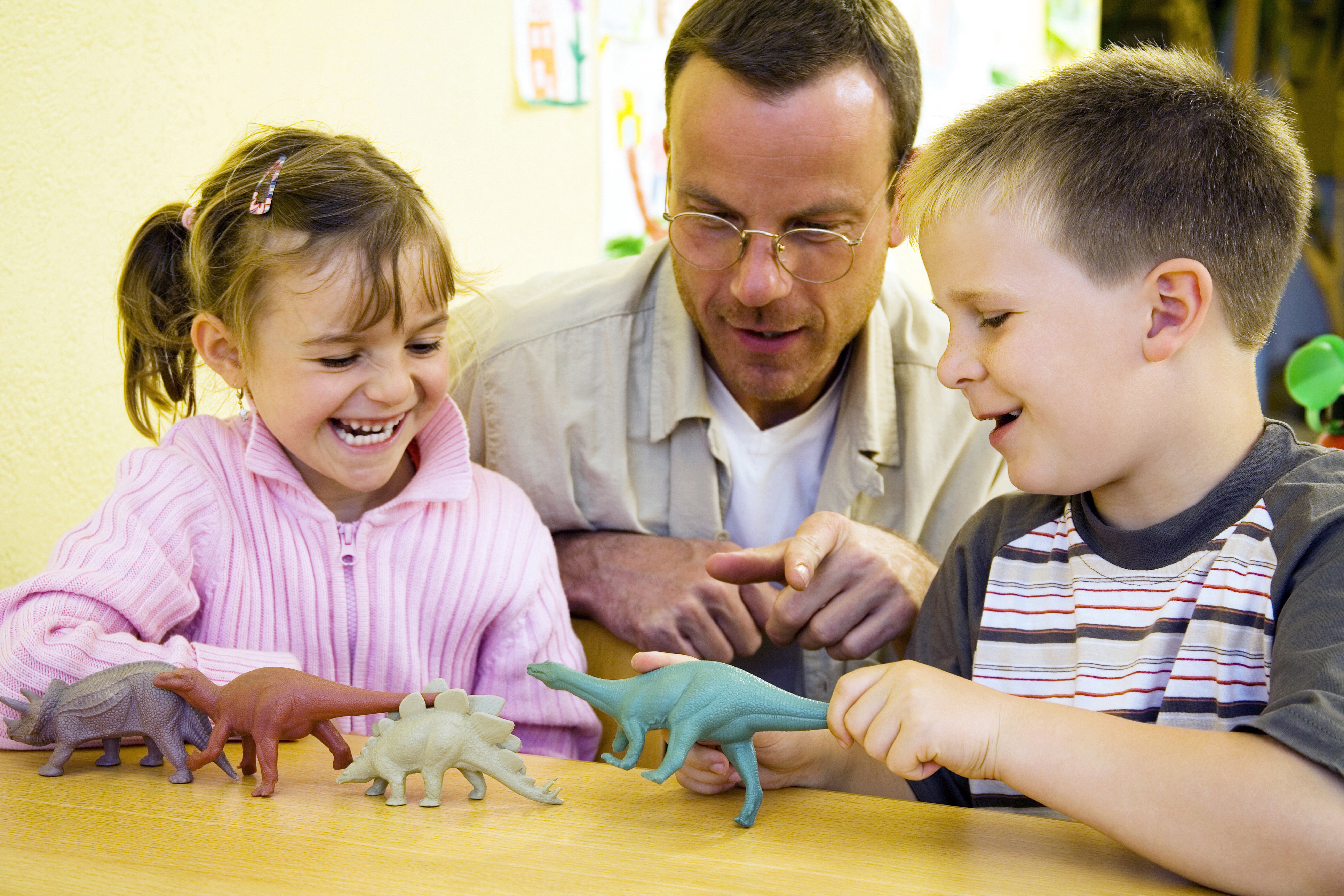 Teacher showing a boy and girl dinosaur models