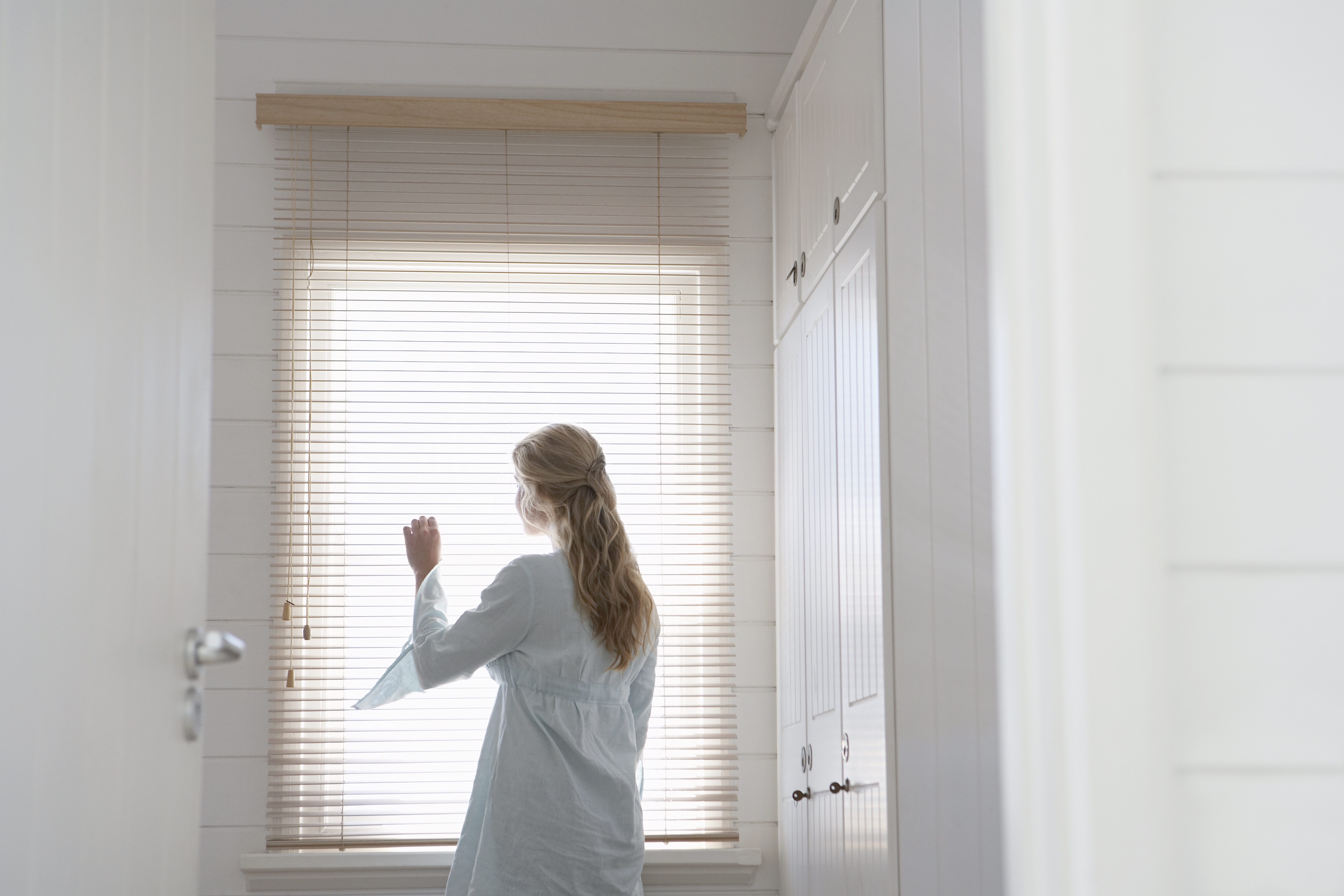 Woman looking out of blinds