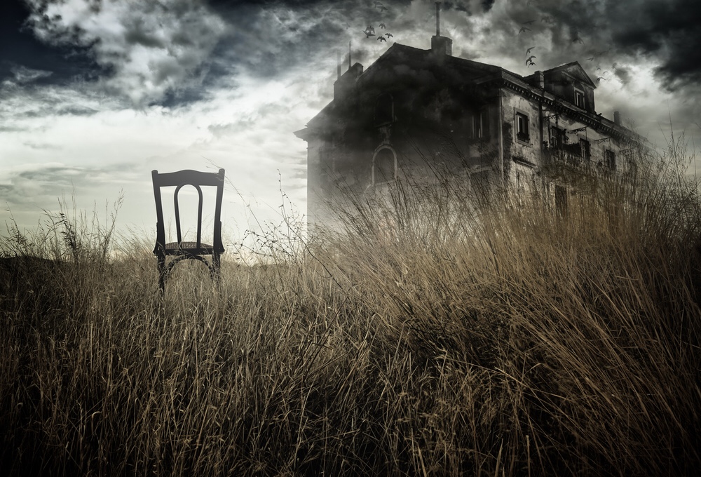 A single chair faces a haunted house