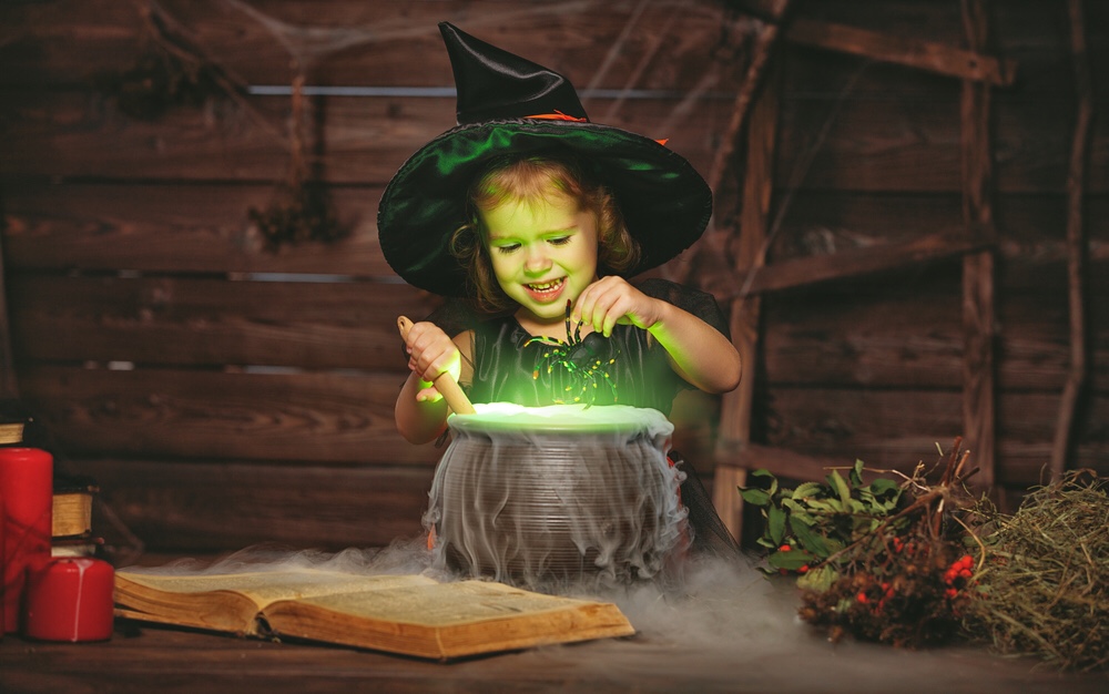 Child witch cooking magic potion in caldron