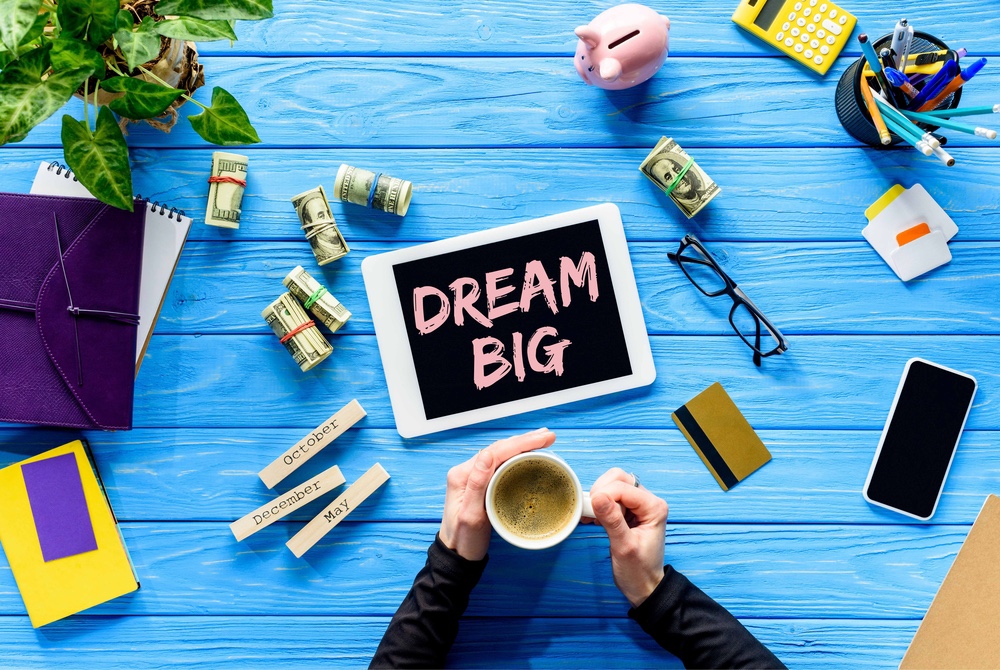 Coffee on a desk with a tablet that says, dream big.