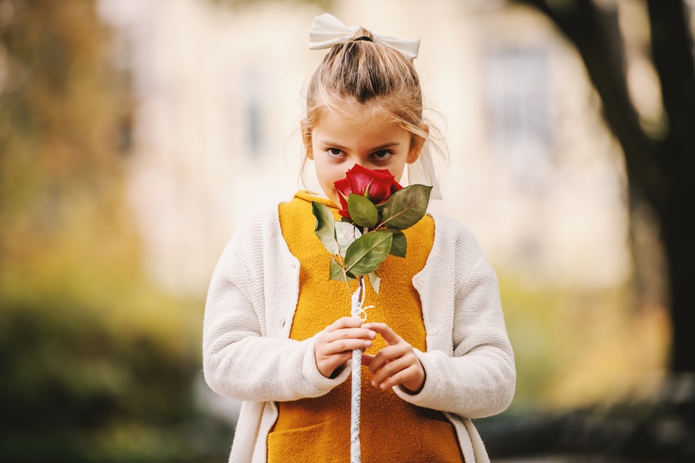 Little girl smelling red rose